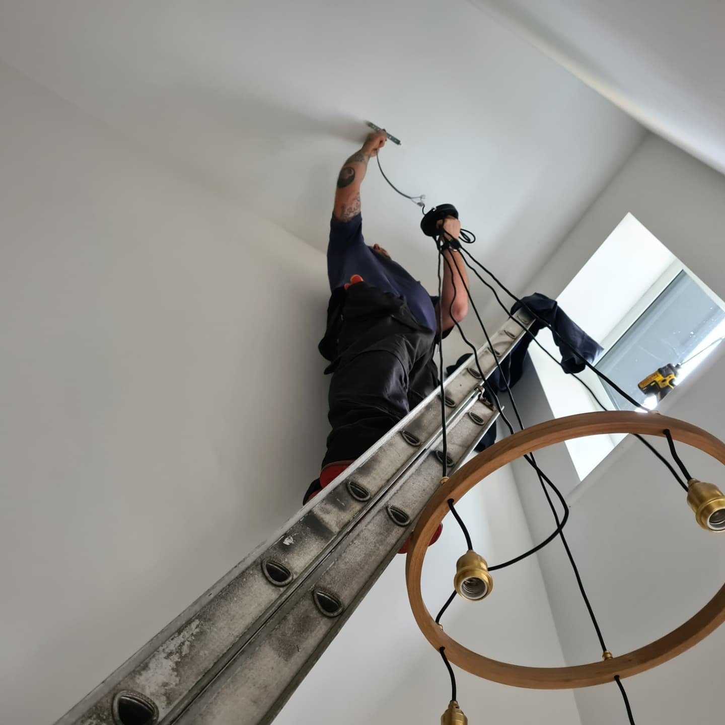 Electrician on ladder fixing ceiling wiring